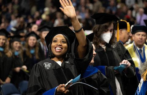 an odu doctoral student waves to the crowd with a diploma in her hand